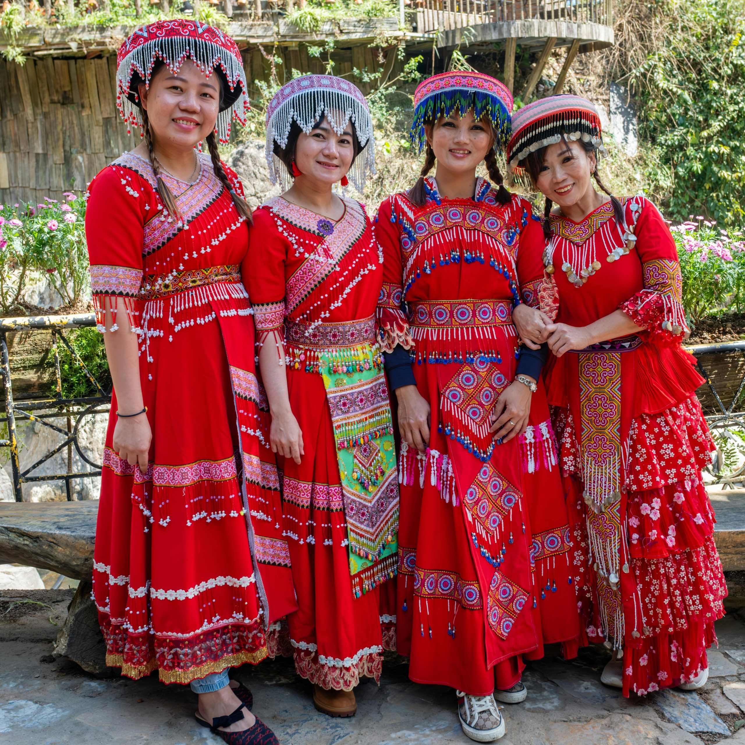 Women in vibrant traditional Hmong dresses in Lao Cai, Vietnam showcasing cultural apparel outdoors.